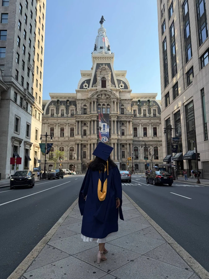 Suruchi in her cap and gown, walking toward Philadelphia City Hall