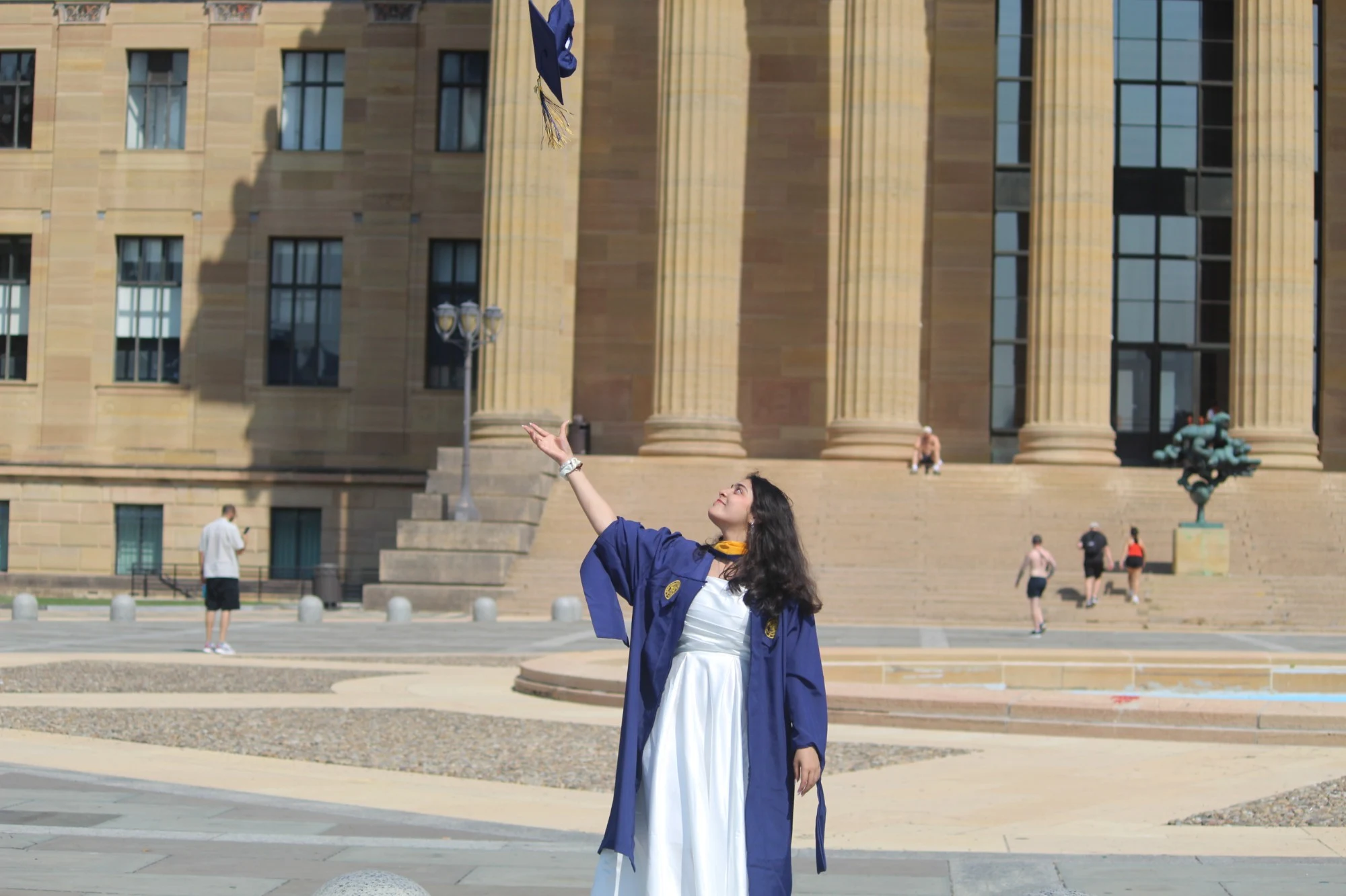 Suruchi throwing her graduation cap in front of the Philadelphia Museum of Art